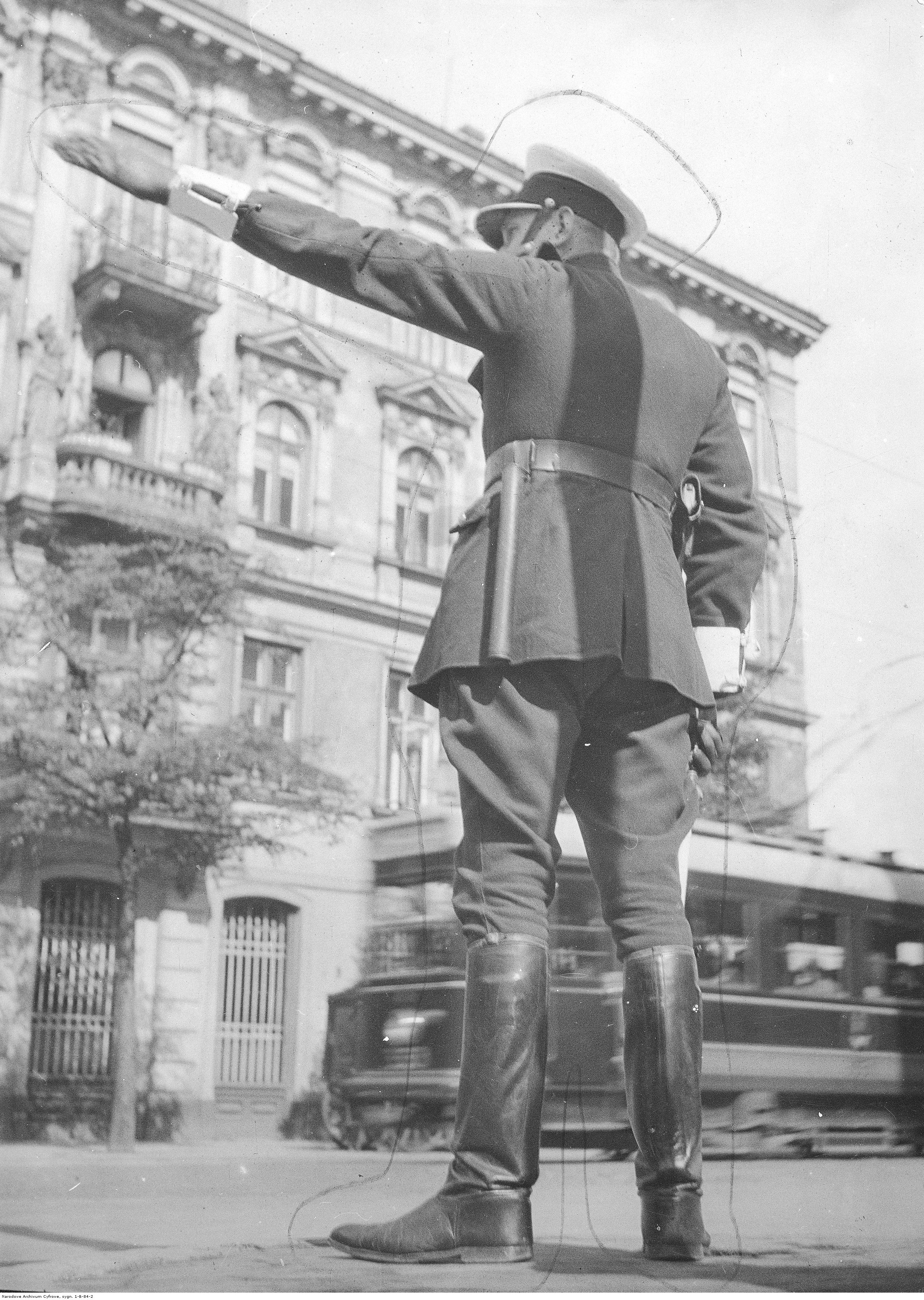 Policjant kierujący ruchem ulicznym, w tle kamienica przy ul. Królewskiej 6. 1932 rok. Narodowe Archiwum Cyfrowe